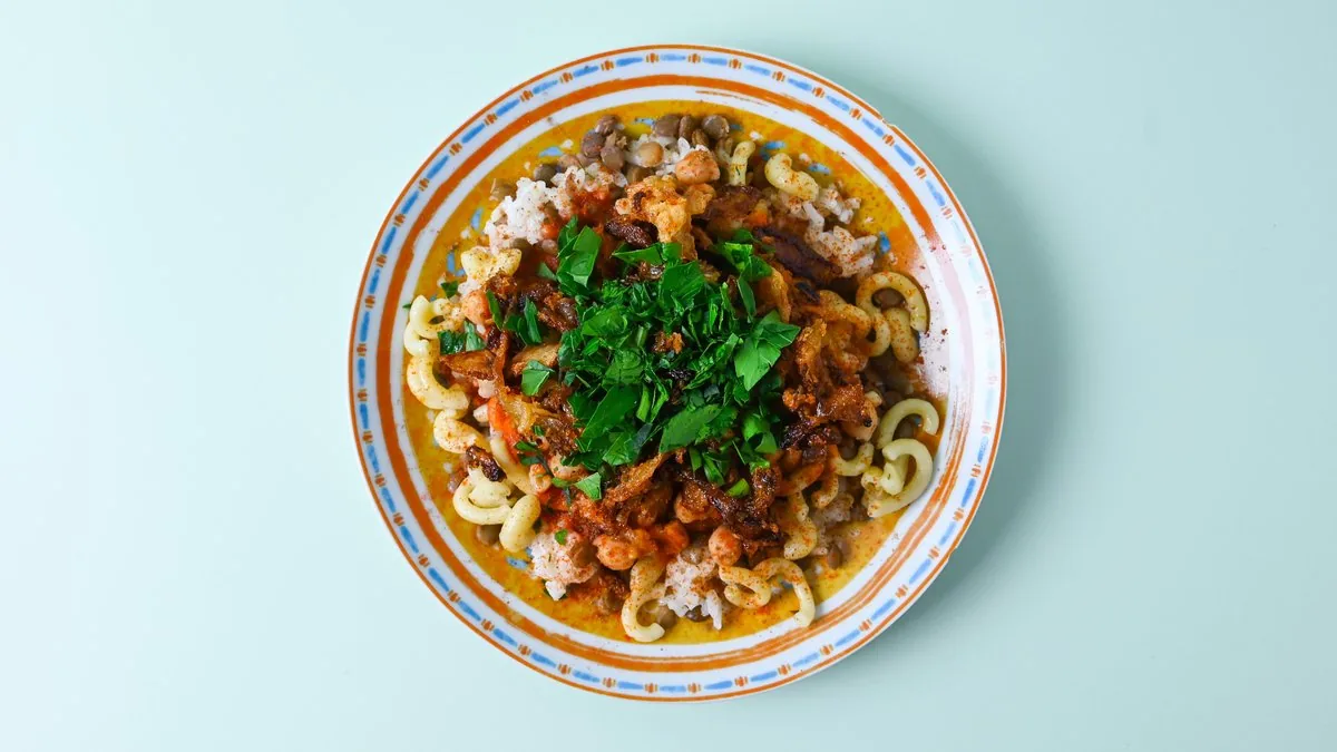 Eine Portion Kuschari: Reis, Nudeln, Linsen und Kichererbsen mit Tomatensauce und Röstzwiebeln.